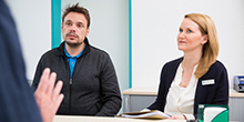 Ein Mann und eine Frau sitzen in einem Büro am Tisch eines Beraters