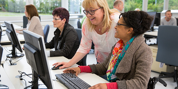 Eine Frau erklärt einer Rehabilitantin etwas am PC