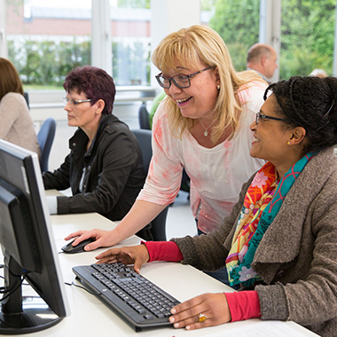 Eine Frau erklärt einer Rehabilitantin etwas am PC
