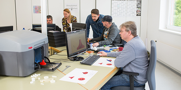 Ein Mann arbeitet lächelnd an einem PC-Arbeitsplatz