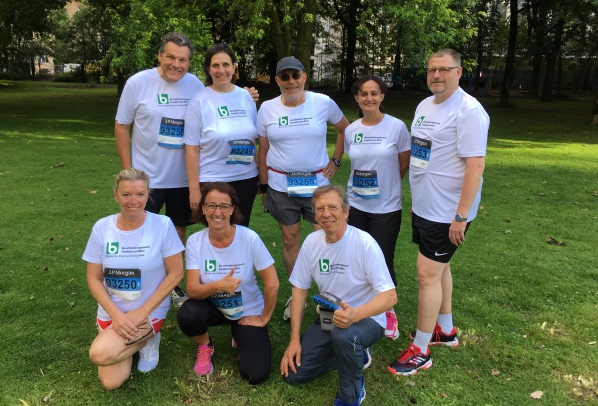 Ein Gruppenbild mehrerer, sportlich gekleideter Personen auf einer Wiese.