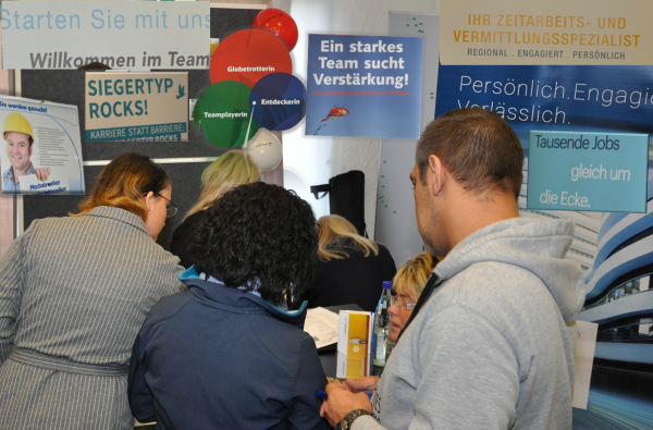 Einige Personen stehen mit dem Gesicht zu seiner Wand mit mehreren Plakaten.