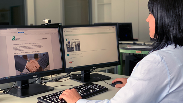 Eine Frau sitzt an einem Schreibtisch vor einem PC, der die Website des BFW Frankfurt zeigt.