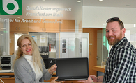 Eine Frau und ein Mann stehen vor der Rezeption des BFW-Frankfurt und halten ein Tablet in den Händen.